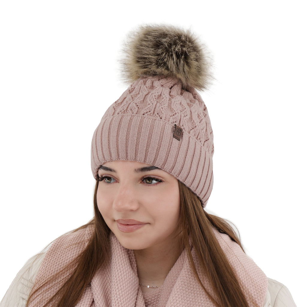 Caciula de dama roz din lana merinos, tricotata cu model impletit si pompon moale din blana sintetica.
