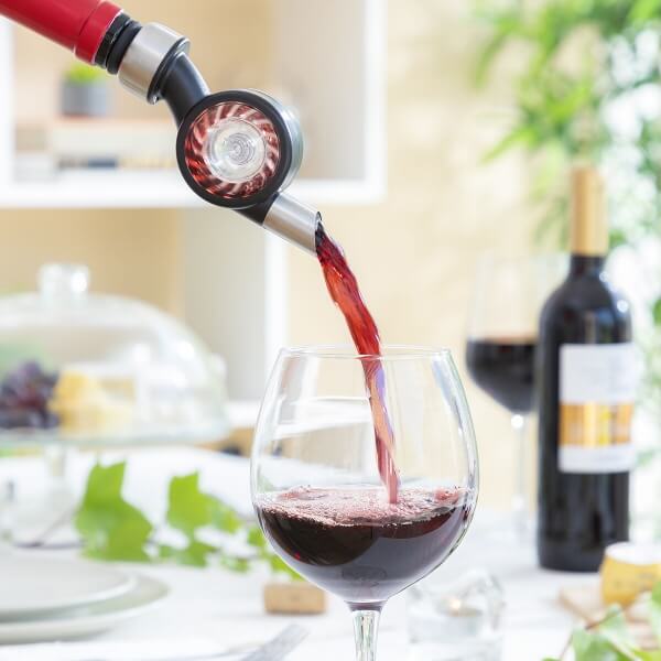 Aerator vin turnând vin roșu, creând spumă în pahar.
