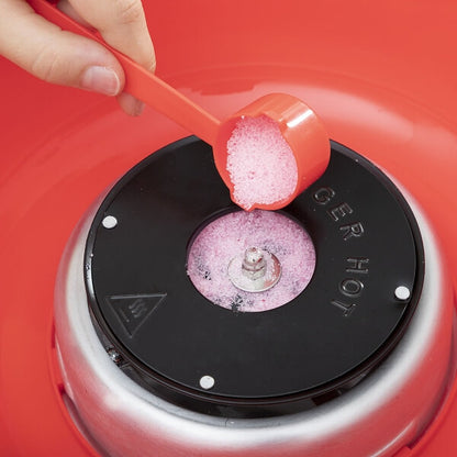 Lingură roșie turnând zahăr roz în aparatul de vată de zahăr.