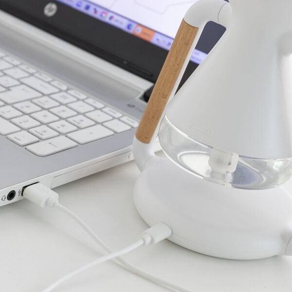 FreshWireless 3 în 1: Difuzor aromaterapie, încărcător wireless și umidificator conectat prin USB la laptop.