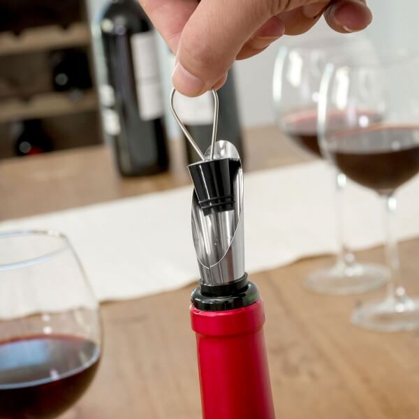 Set cadou accesorii vin - 5 piese, prezentând introducerea dispozitivului de turnare în sticla de vin.